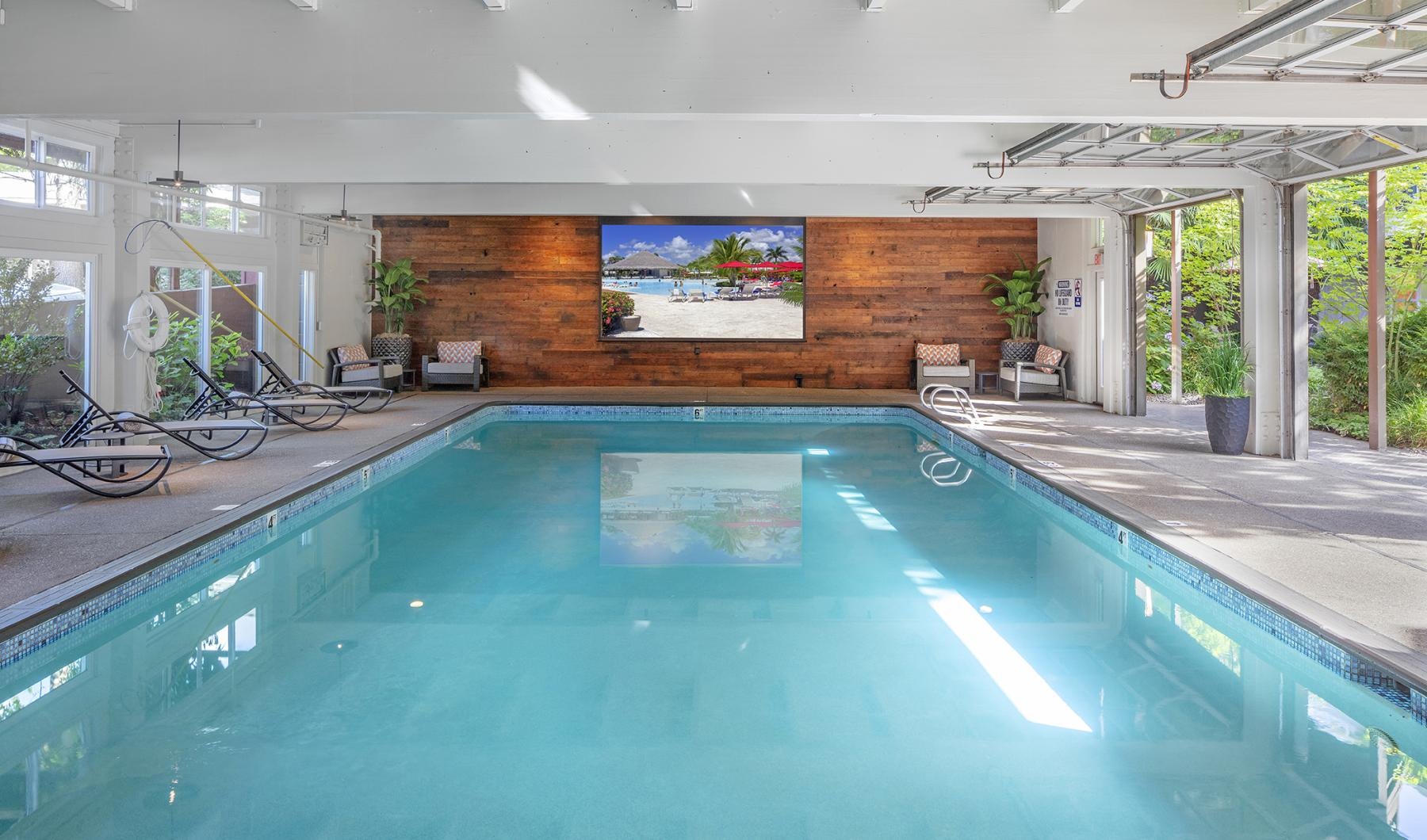 an indoor swimming pool with chairs and a tv