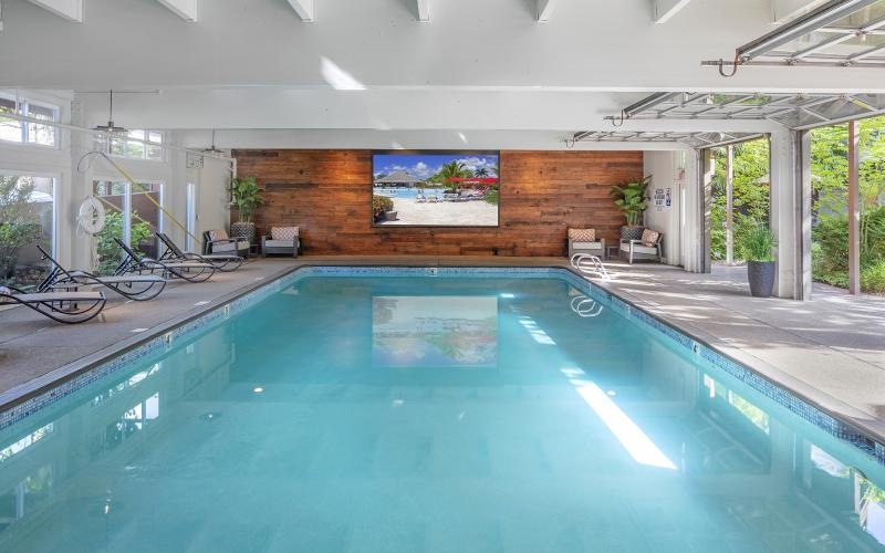 an indoor swimming pool with chairs and a tv